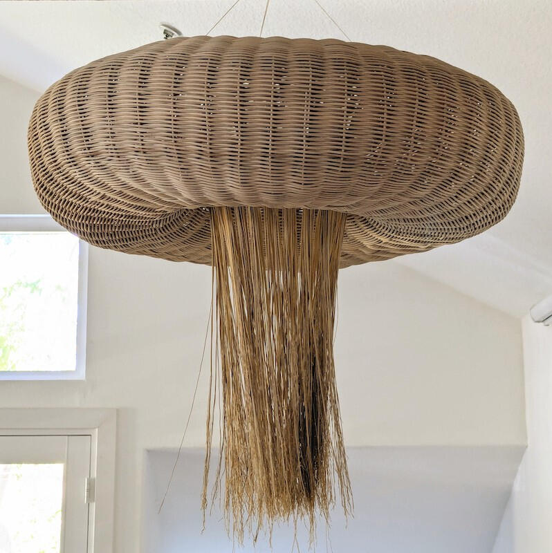 large donut-shaped basketry reed sculpture hanging from the ceiling, with long broomcorn stalks hanging down from the center